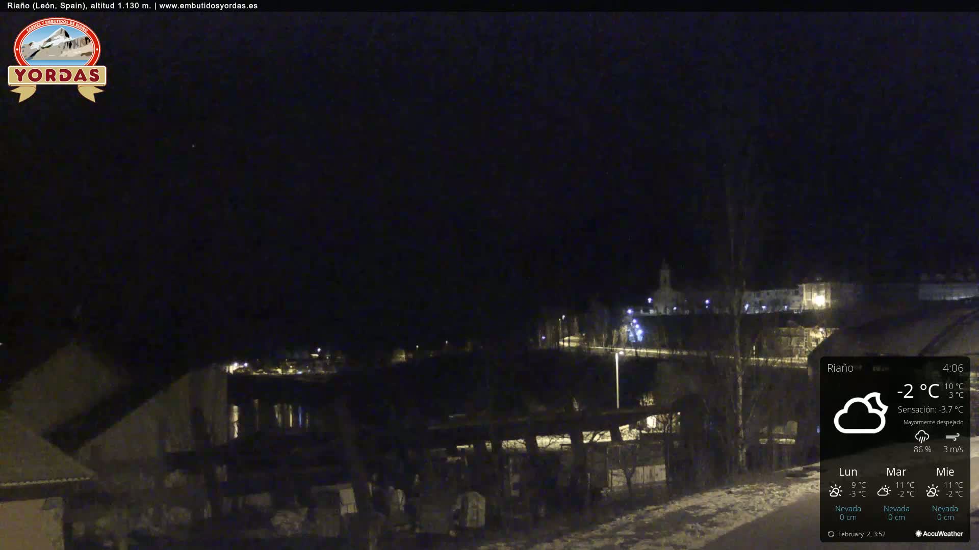 A nighttime view of a snow-covered town under a mostly clear sky.