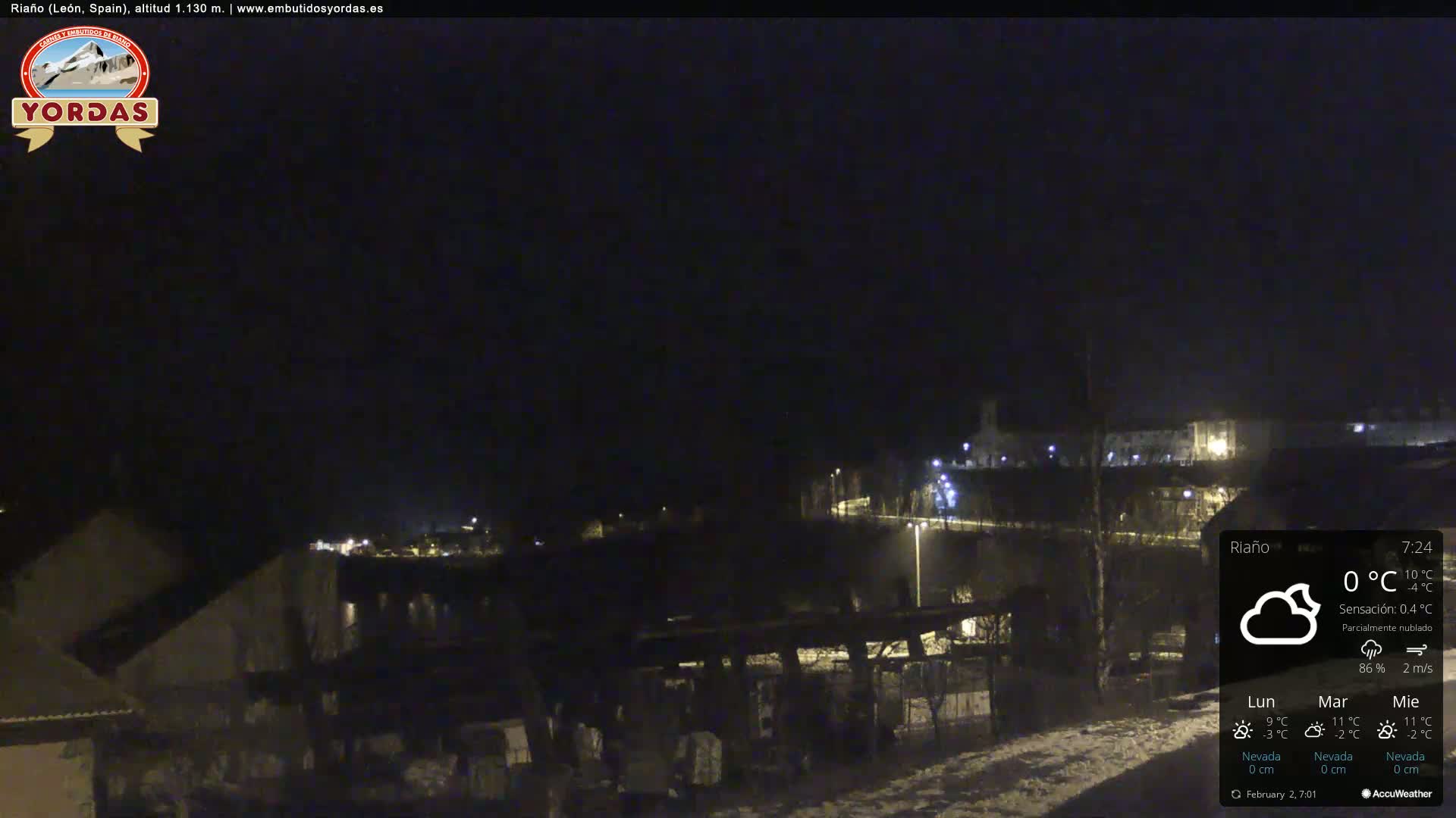 A nighttime view of a snow-covered town under a partly cloudy sky.