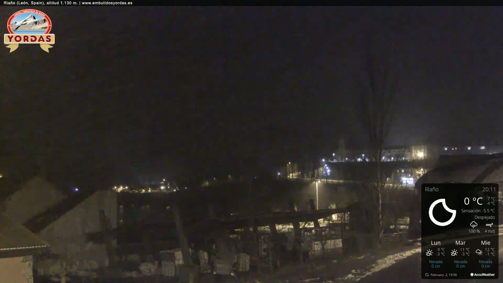 A nighttime, clear view of a snow-covered town, illuminated by streetlights.