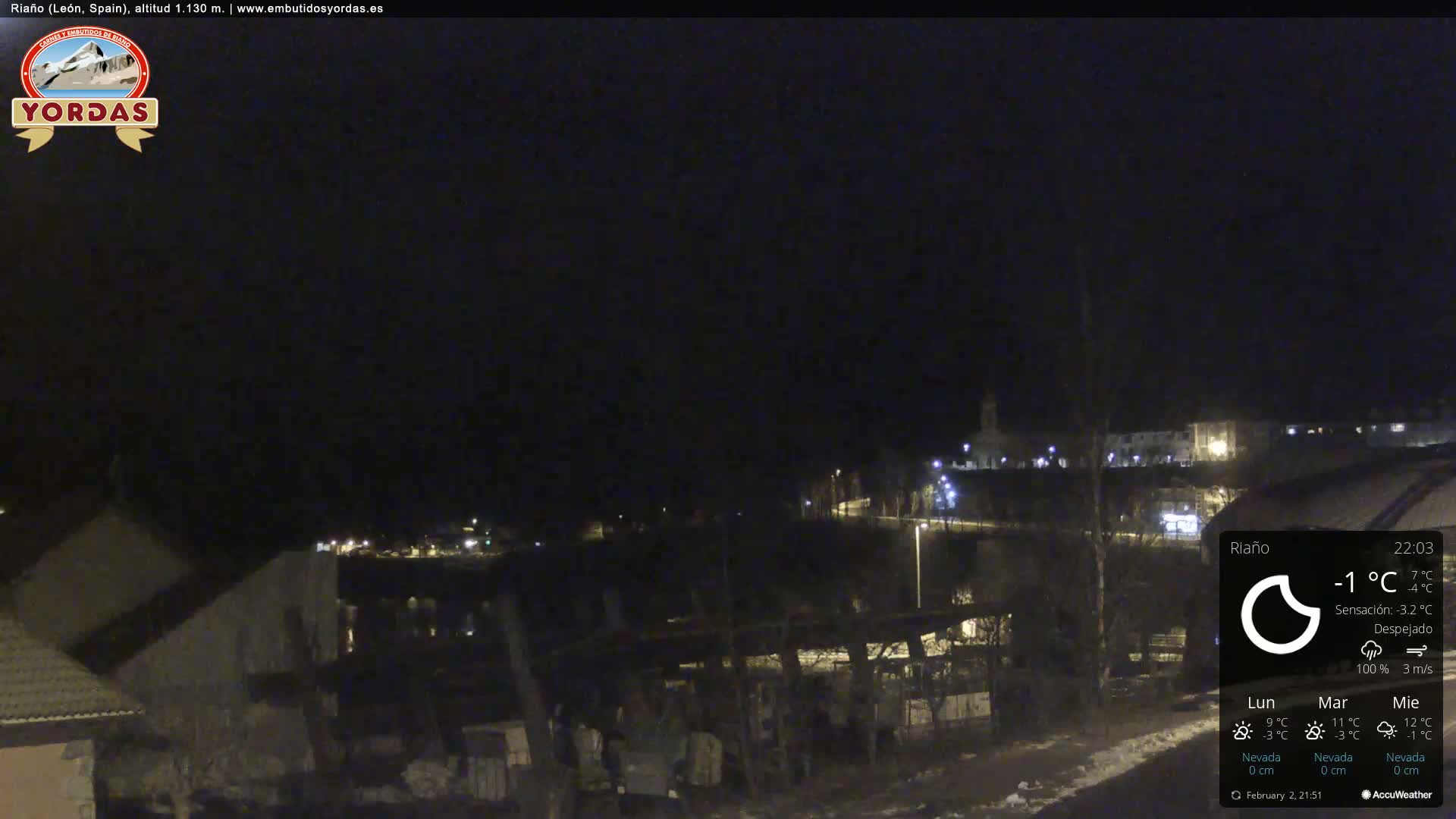 A nighttime view of a snow-dusted town, under a clear sky.