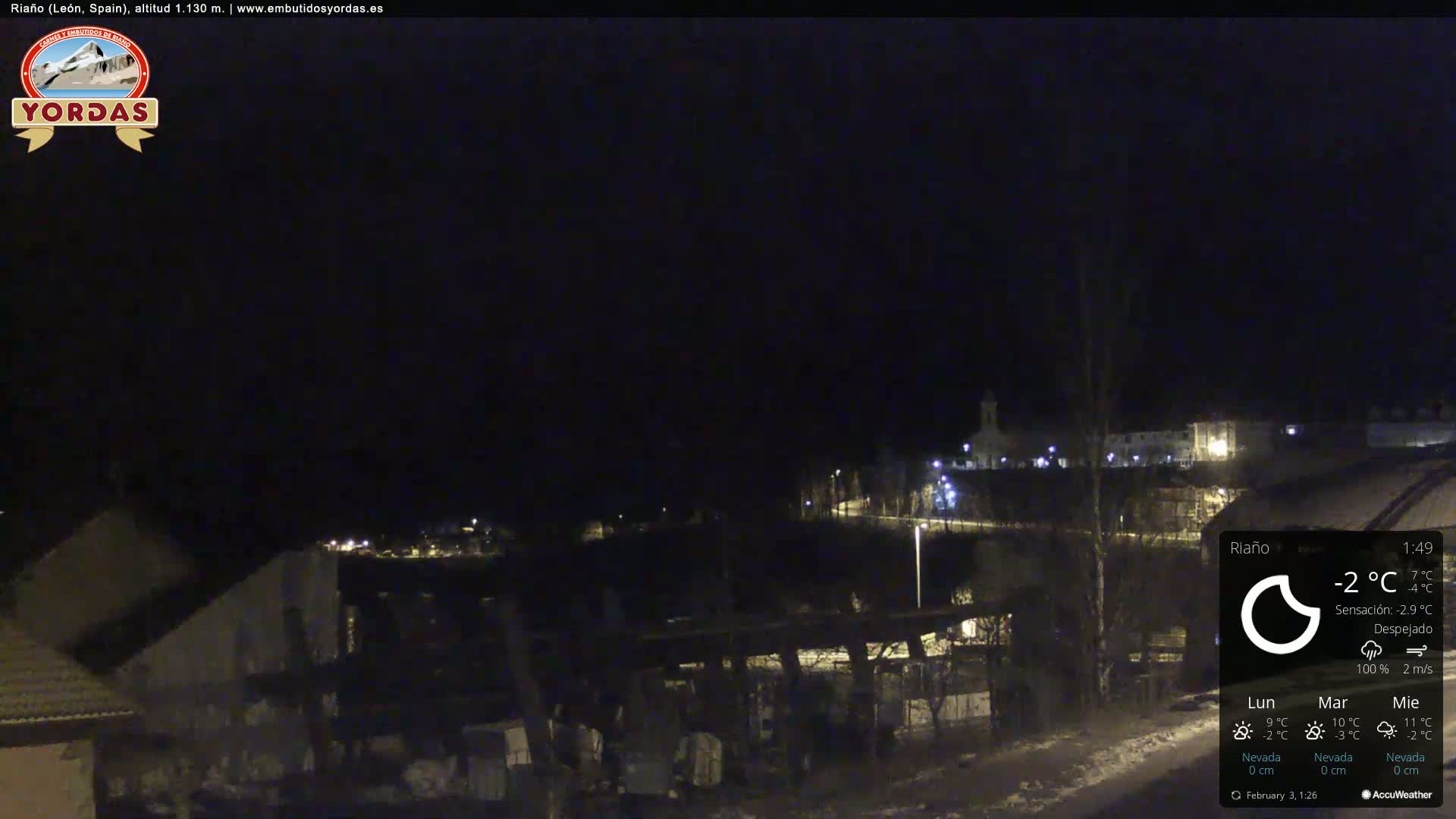 A nighttime view of a small town with some lights visible, under a clear sky.