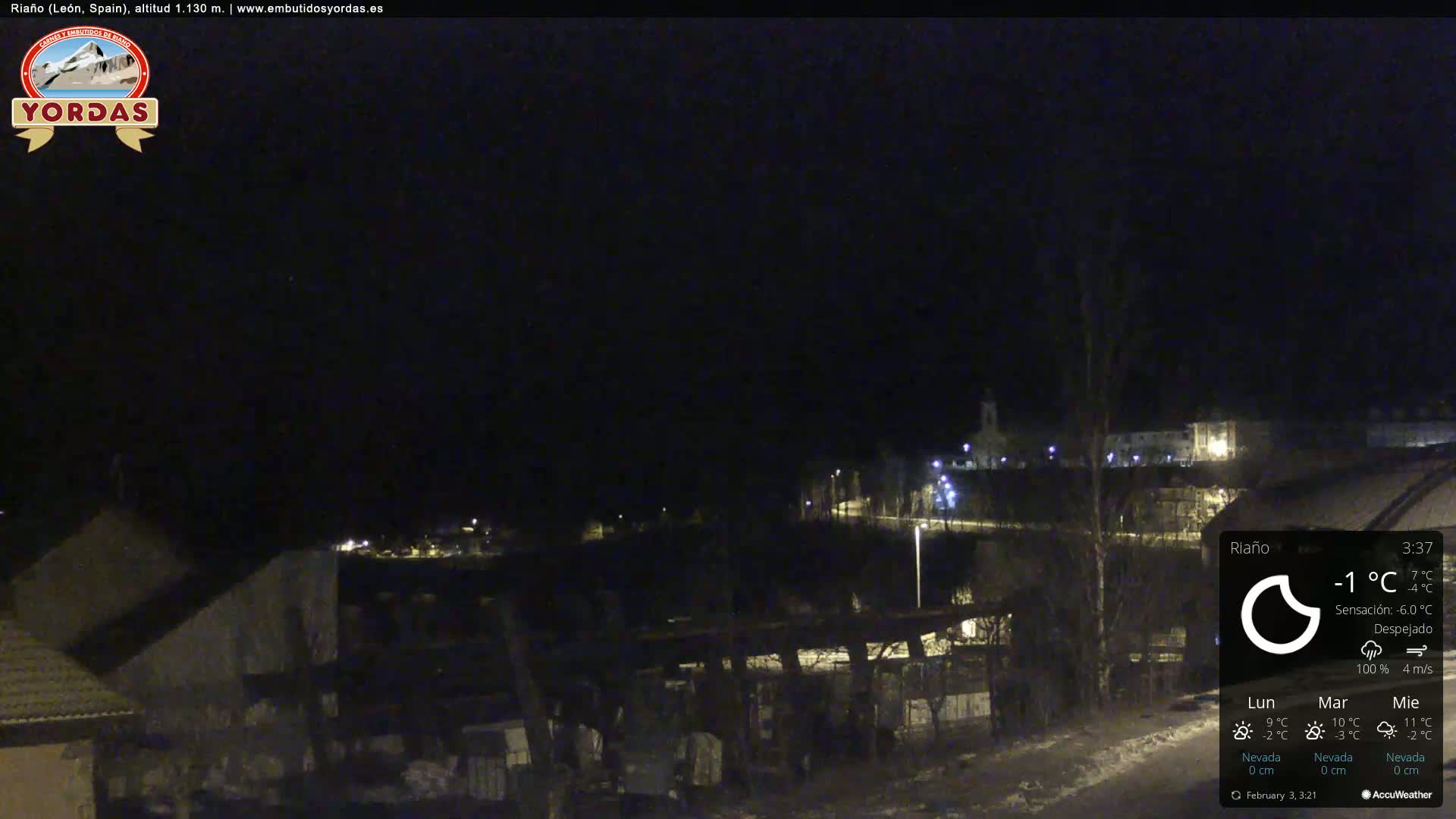 A nighttime, clear view of a small town, partially snow-covered, illuminated by streetlights.