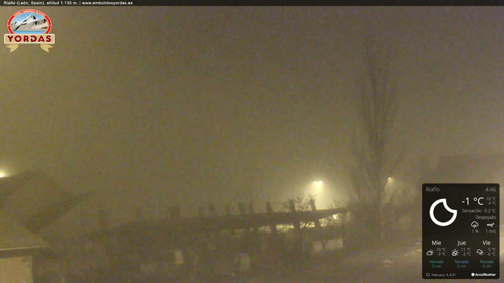A foggy, nighttime scene shows dimly lit structures and trees under a muted yellow sky.