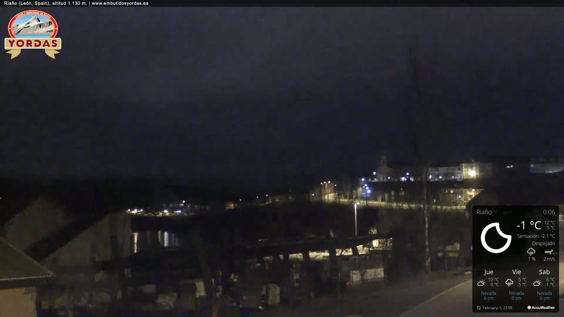 A nighttime view of a town, under clear skies, with a few lights visible.