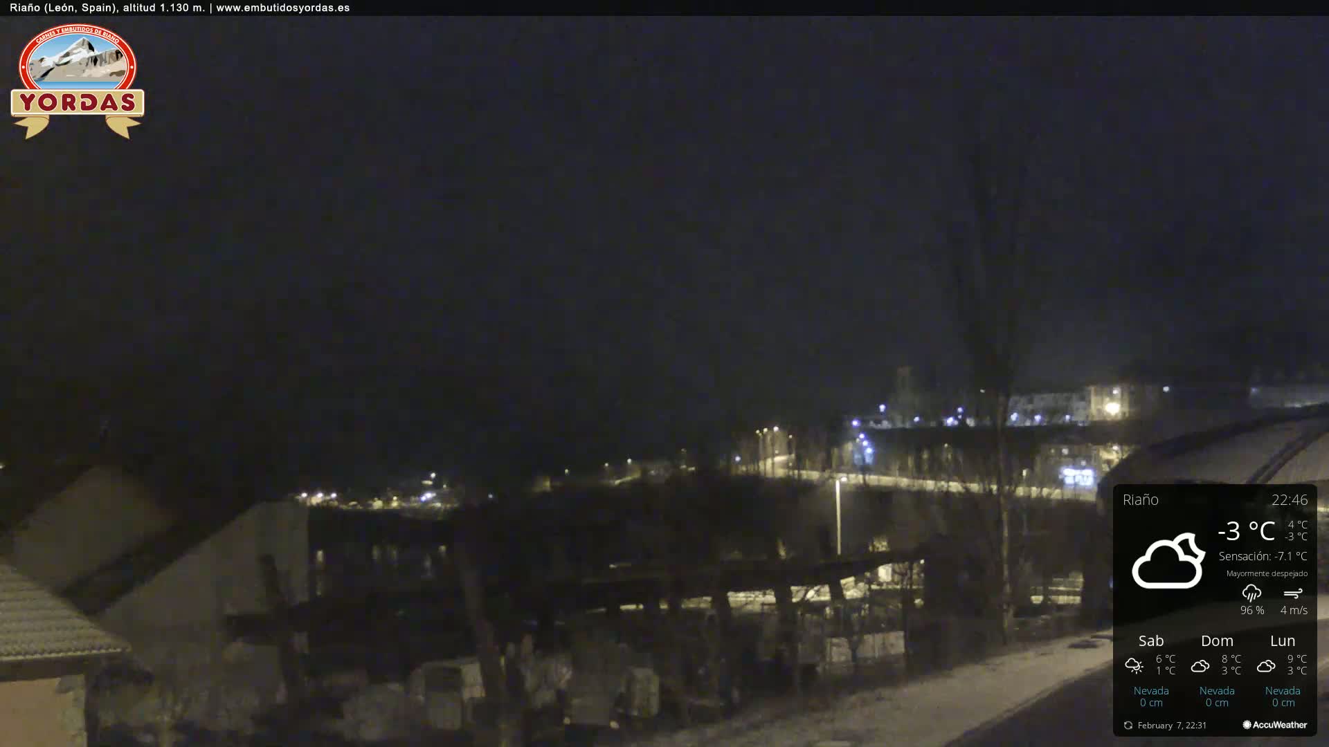 A nighttime view of a snow-covered town under a mostly clear sky.