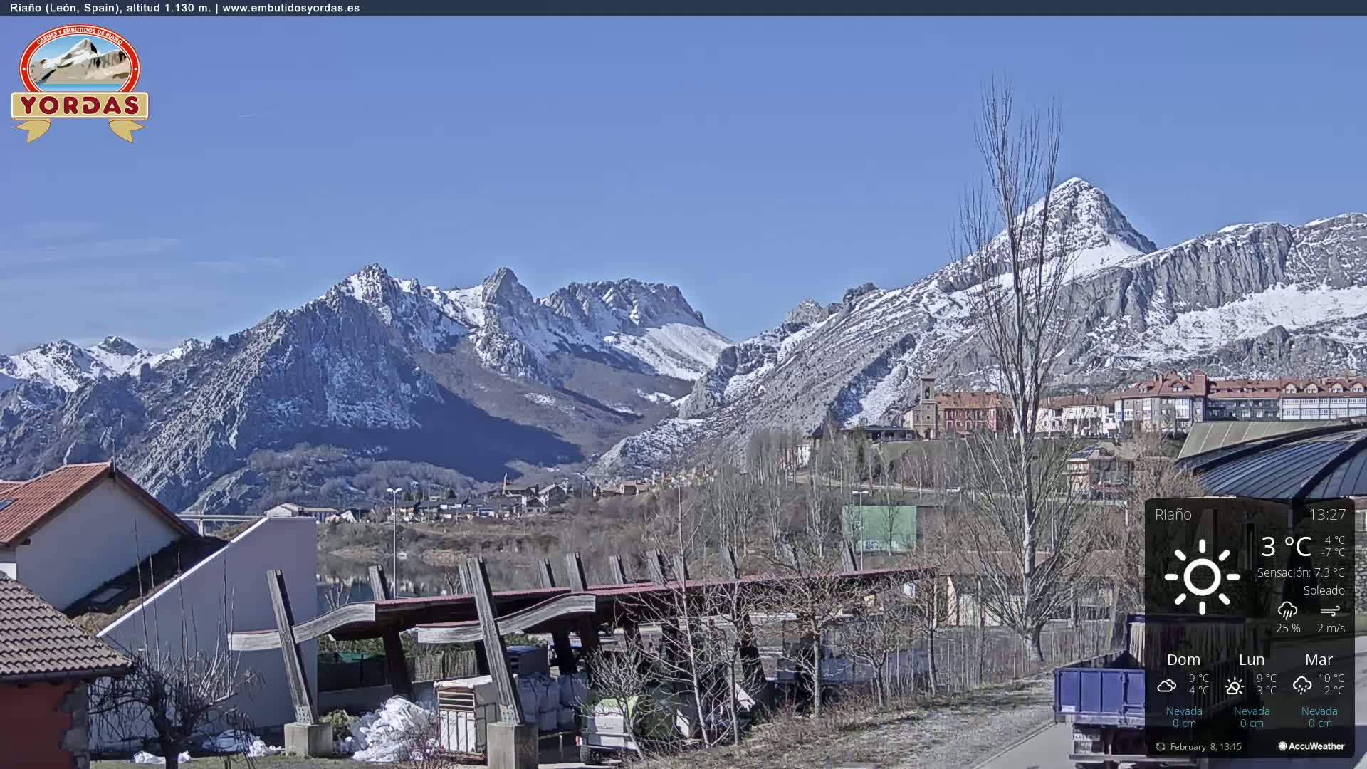 A sunny day reveals a snow-capped mountain range overlooking a town nestled in a valley.