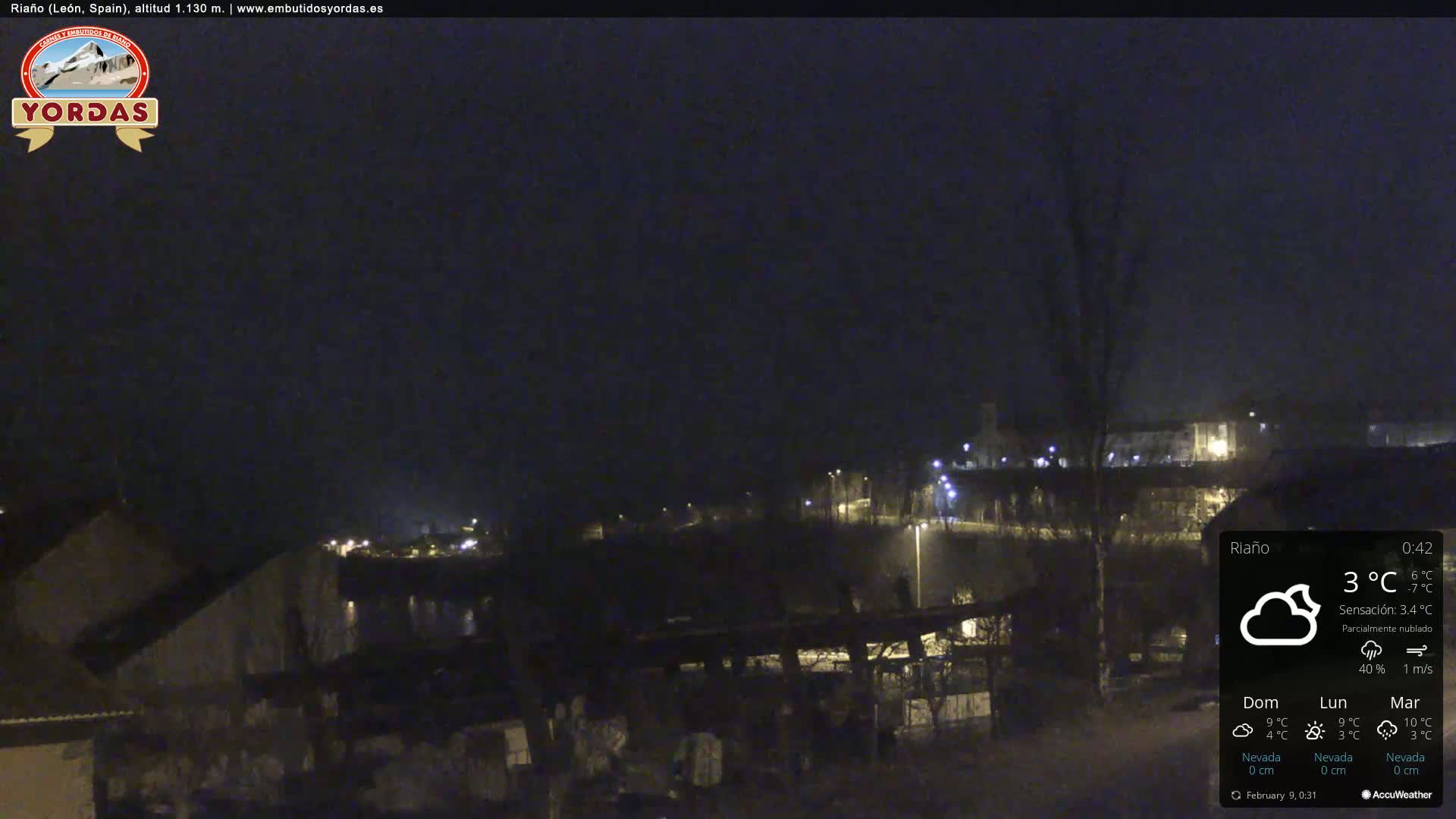 A nighttime view of a town, partially obscured by darkness and partly cloudy conditions.