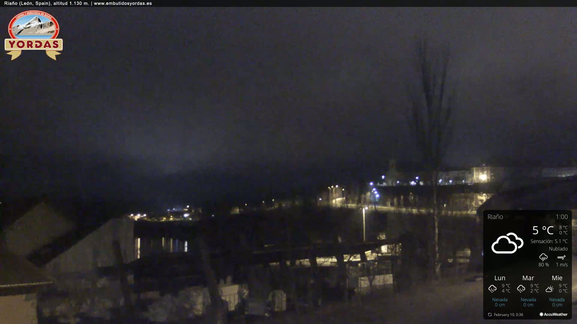 A nighttime view of a town under a cloudy sky, with some lights visible.