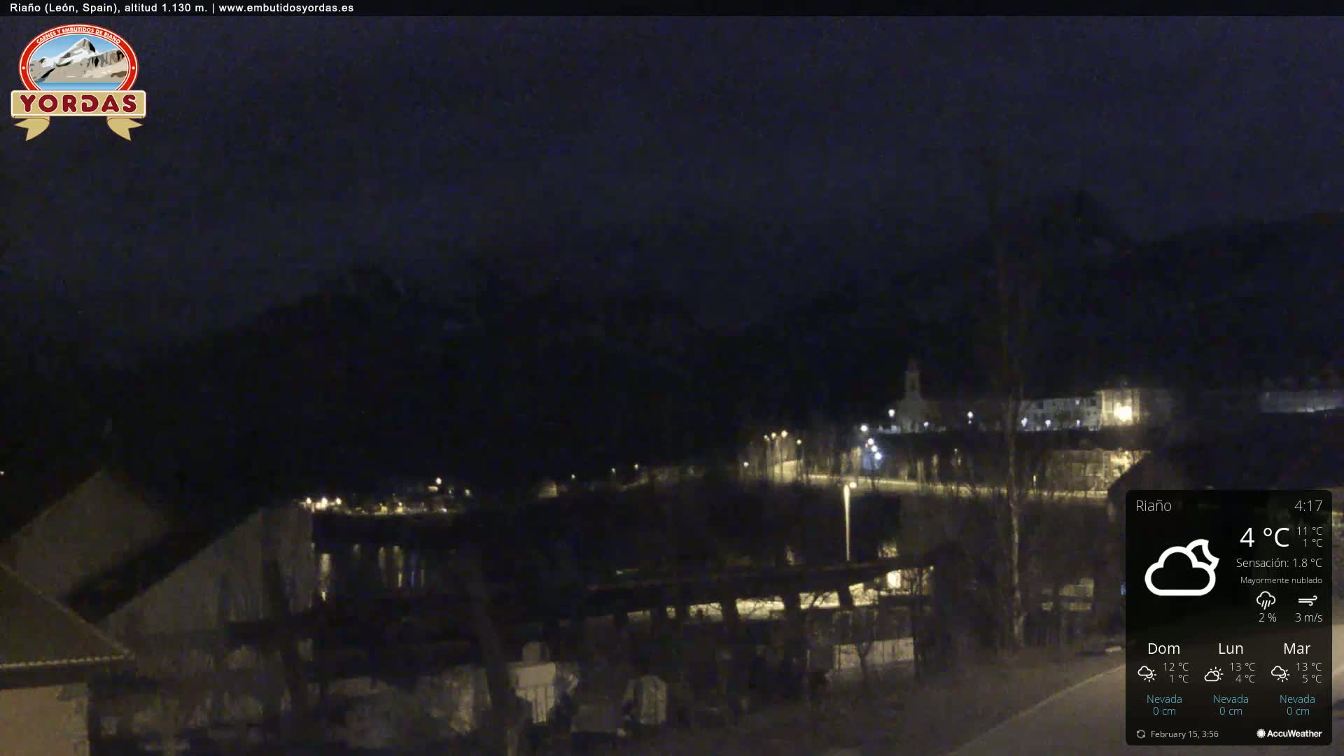 A nighttime view of a small town nestled in a valley, under mostly cloudy skies.