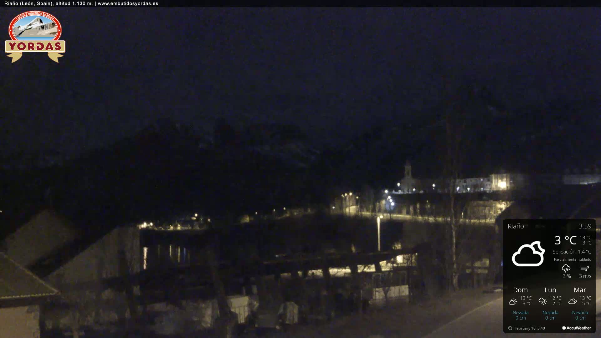 A nighttime view of a small town nestled in a valley, partially cloudy with a light breeze.