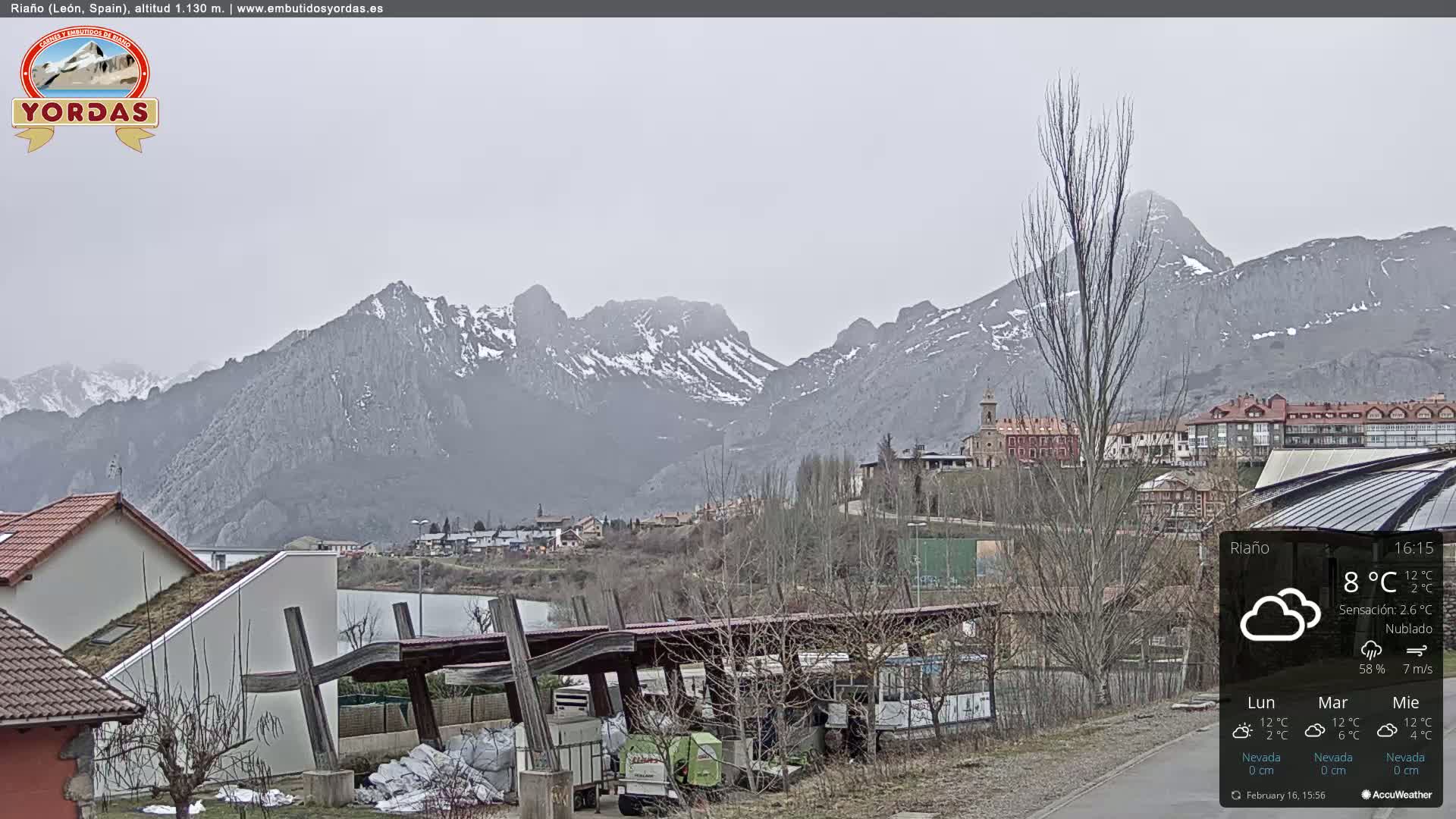 A cloudy day reveals a town nestled at the base of snow-dusted mountains.