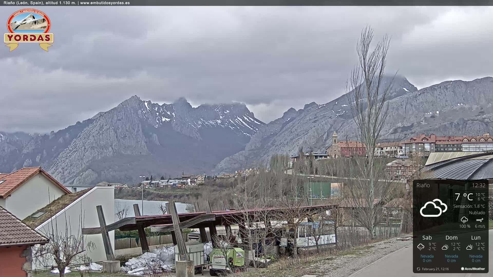 A cloudy day reveals a town nestled at the foot of snow-capped mountains.