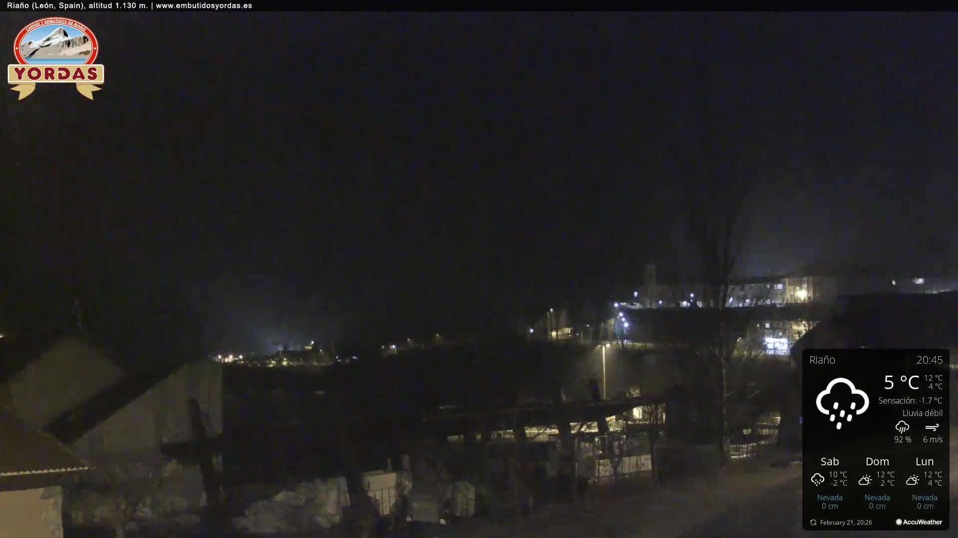 A nighttime view of a small town under a dark sky with light rain.