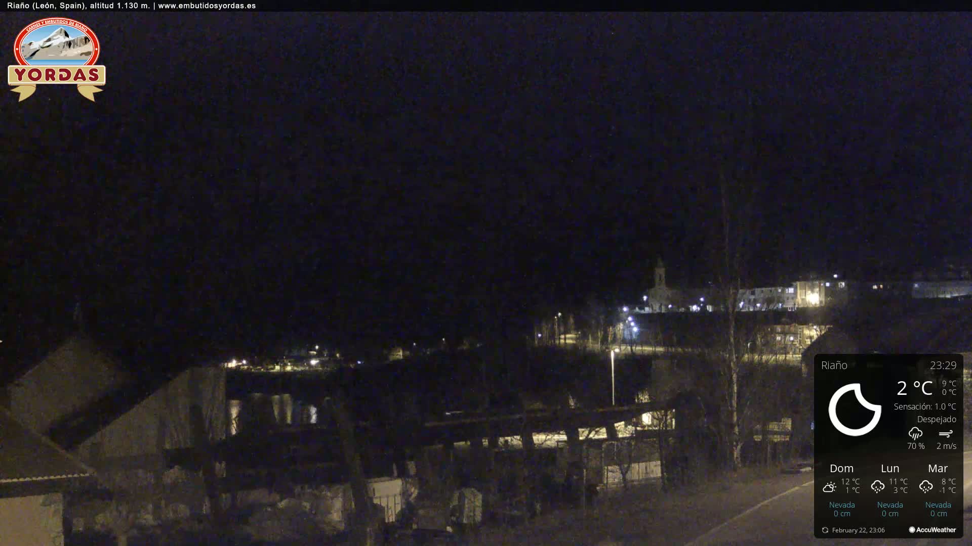A nighttime view of a small town illuminated by streetlights under a clear, dark sky.