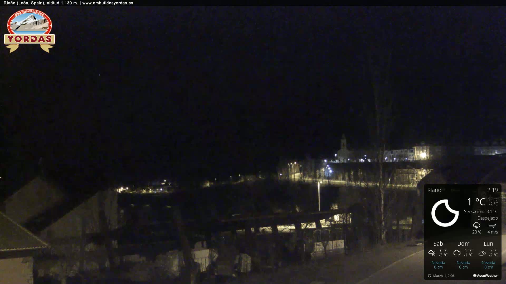 A nighttime long shot of a small town, sparsely lit, under a clear, dark sky.