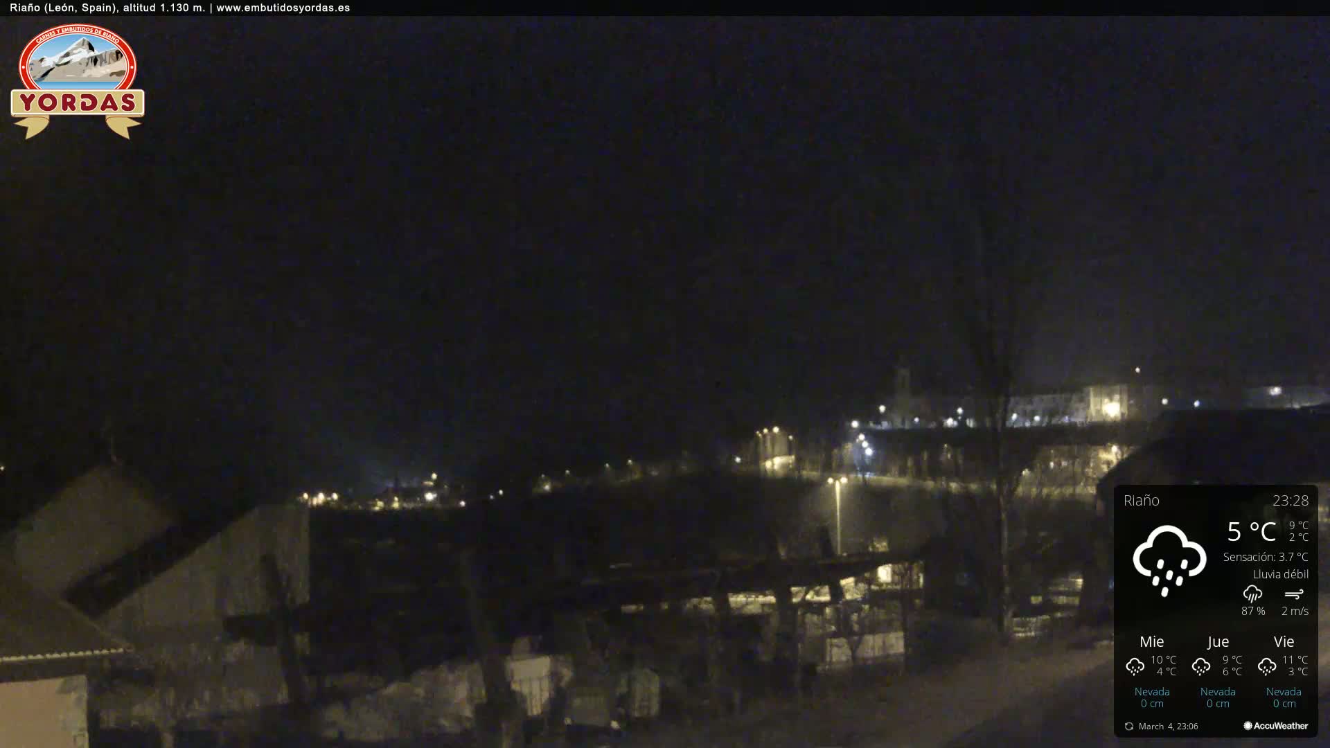A nighttime view of a town under a dark sky with light rain and a temperature of 5°C.