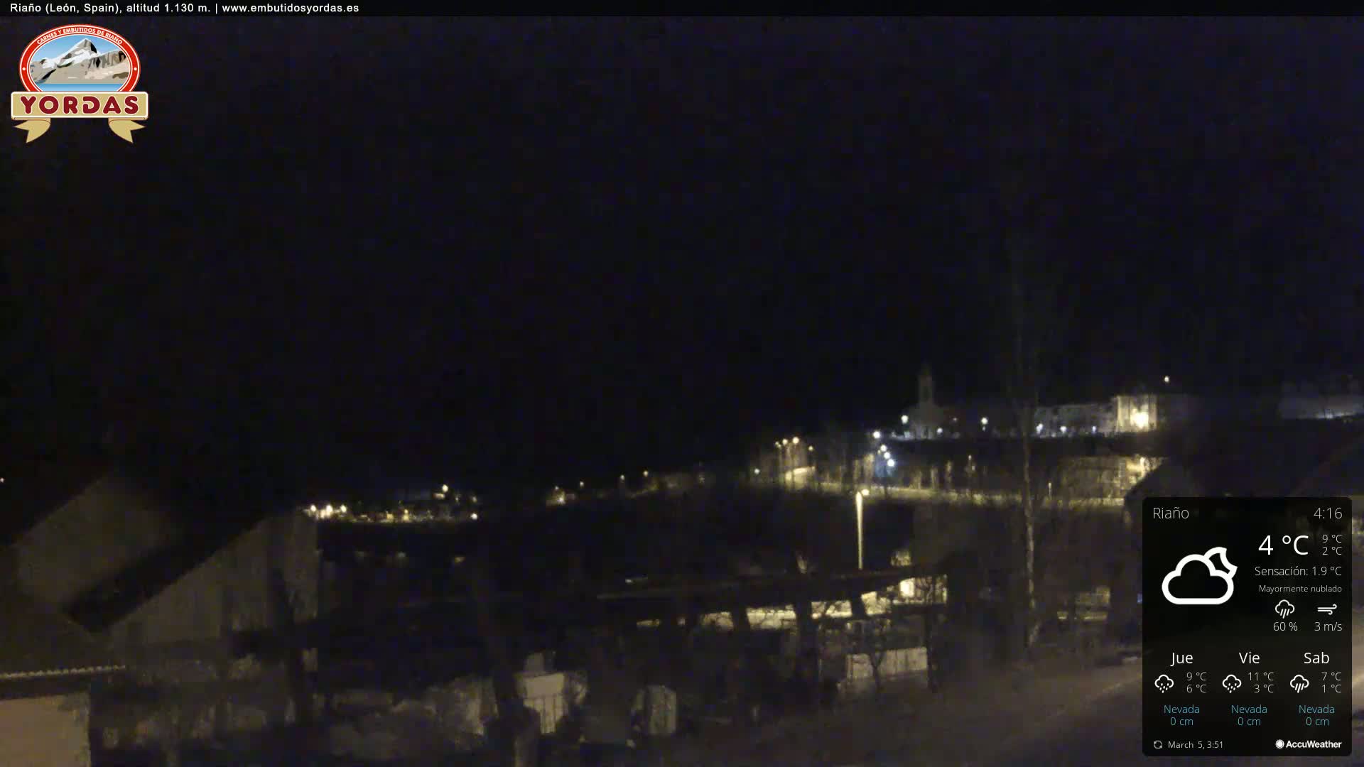 A nighttime view of a dimly lit town under a mostly cloudy sky.