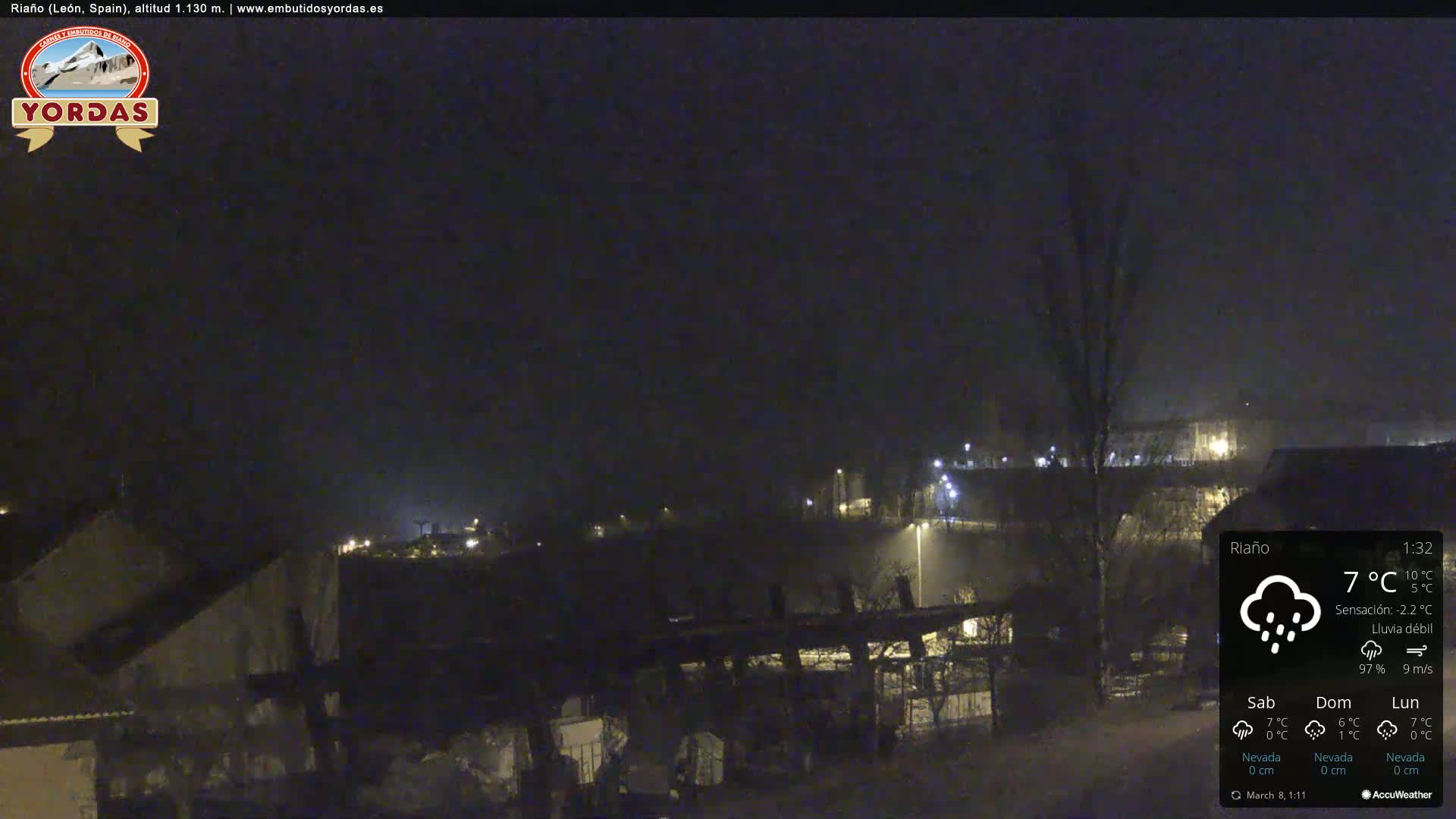 A nighttime view of a town under a dark, lightly rainy sky.