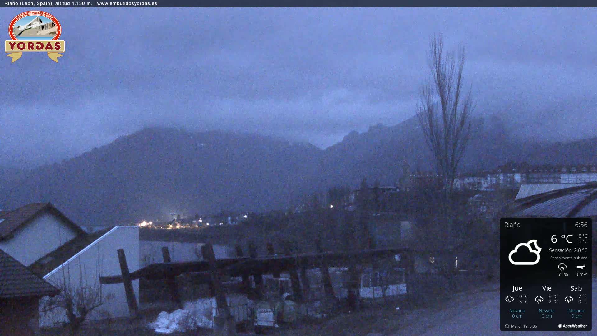 A partly cloudy, cool evening scene overlooking a town nestled in a valley, with mountains in the background.
