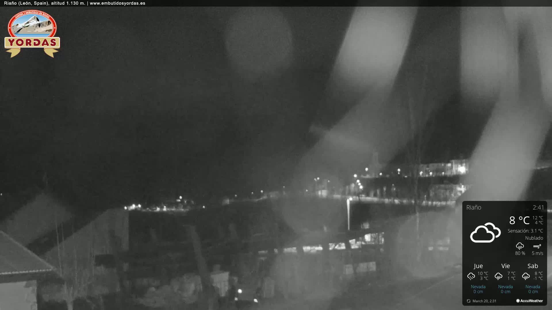 A nighttime, cloudy view of a town, partially obscured by fog or mist.