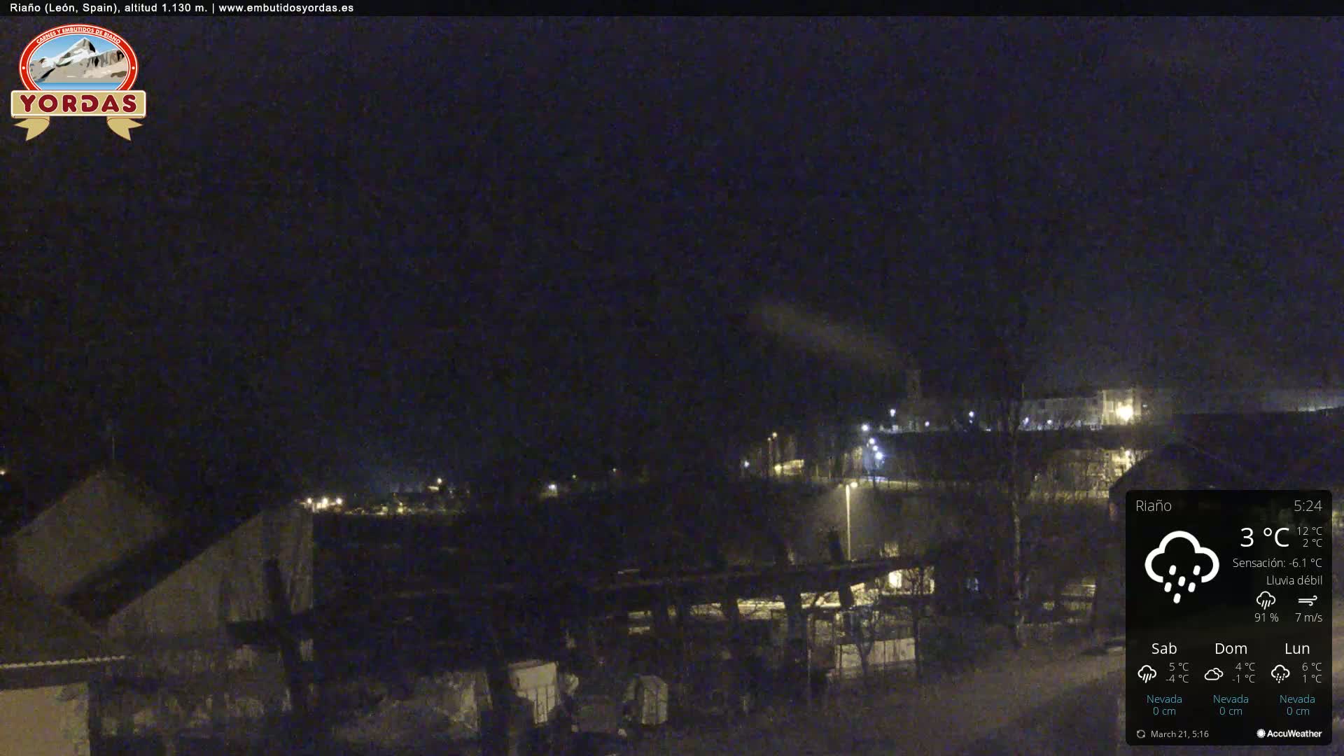 A nighttime view of a small town under a dark sky with light rain.