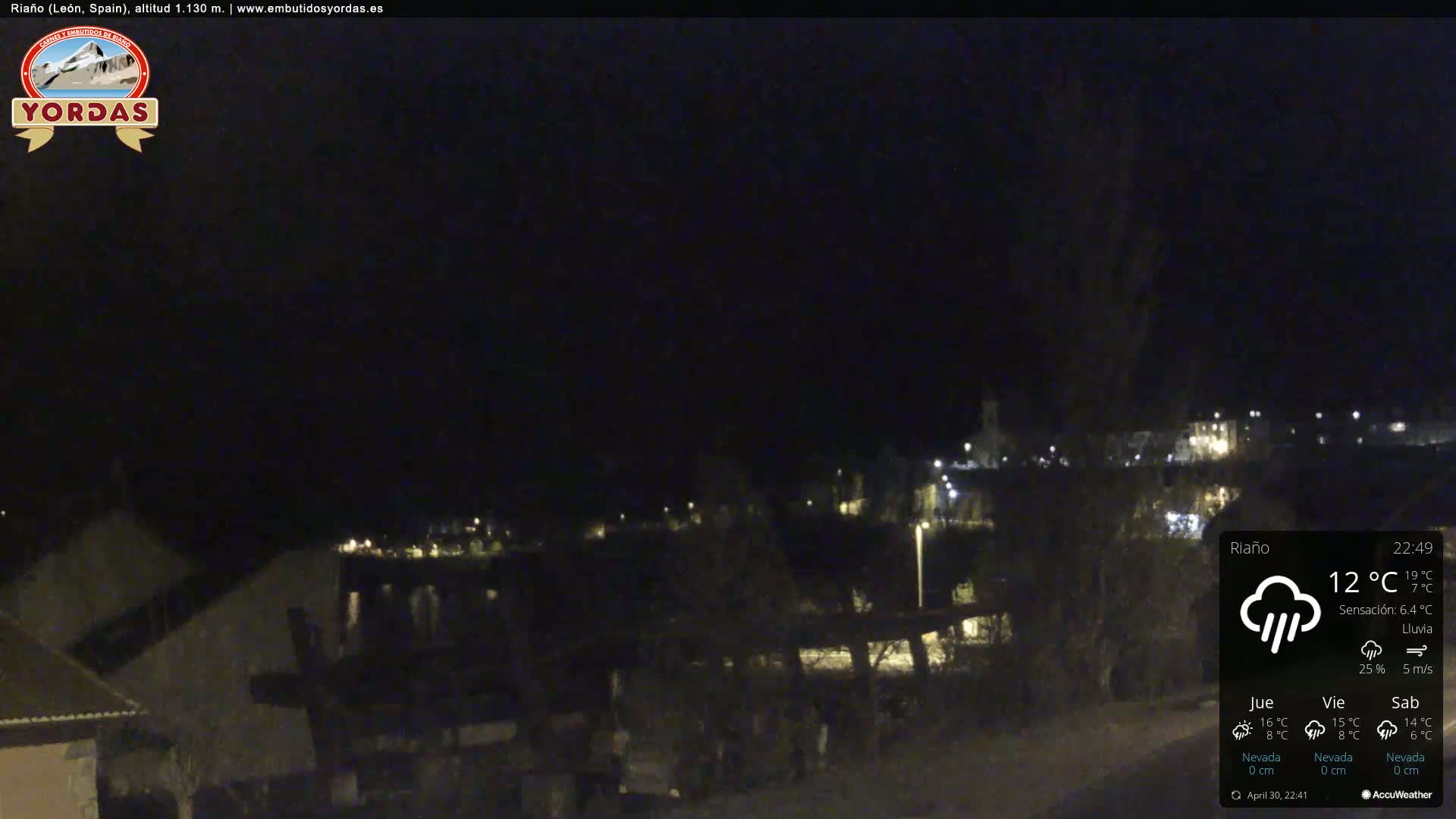 A nighttime view of a town with light rain under a dark sky.