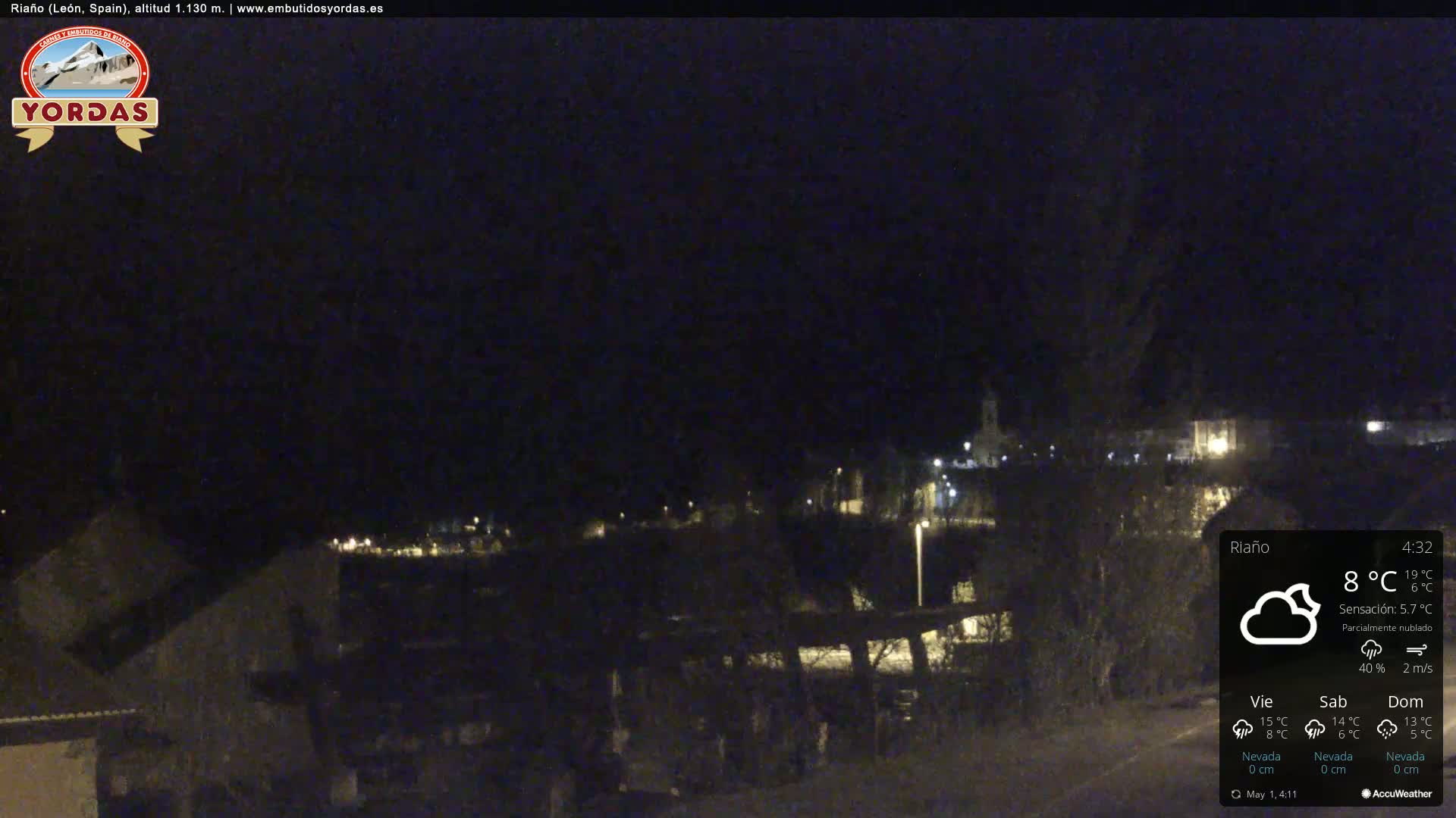 A nighttime view of a dimly lit town under a partly cloudy sky.