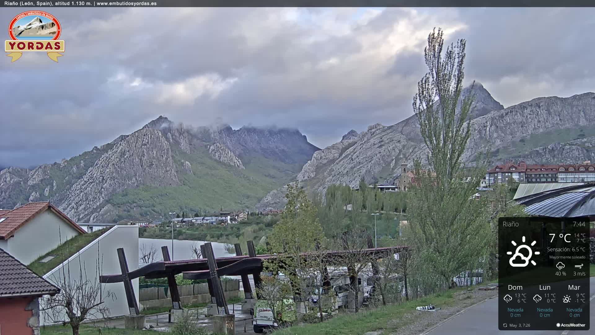 A mostly cloudy day reveals a mountain range in the distance, with a town and buildings situated in the foreground.