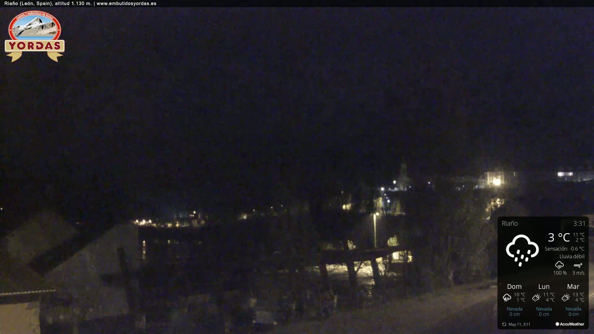 A nighttime view of a small town under a dark sky with light rain.
