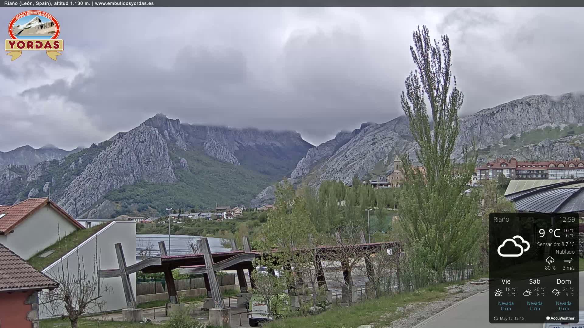 A cloudy day reveals a mountainous landscape, with a town nestled in the valley below and modern architecture in the foreground.
