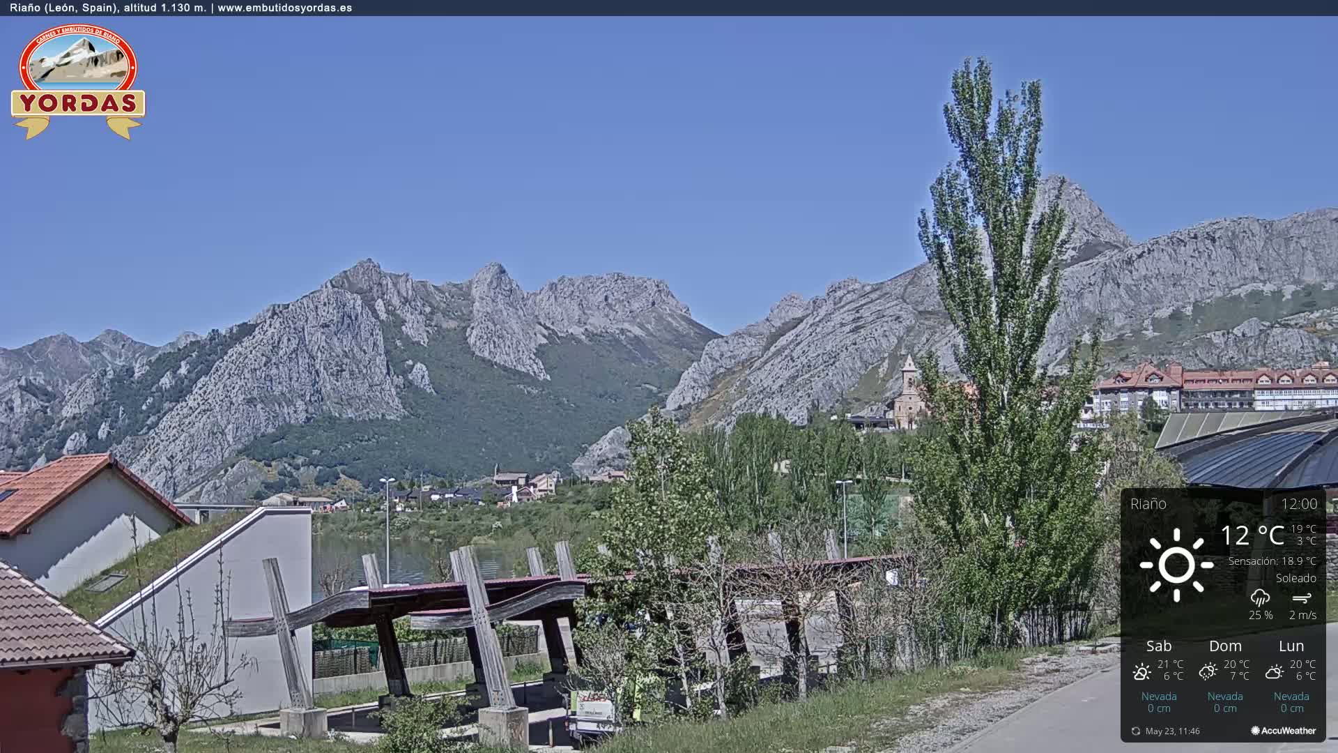 A sunny view of a town nestled in a valley surrounded by rocky mountains.