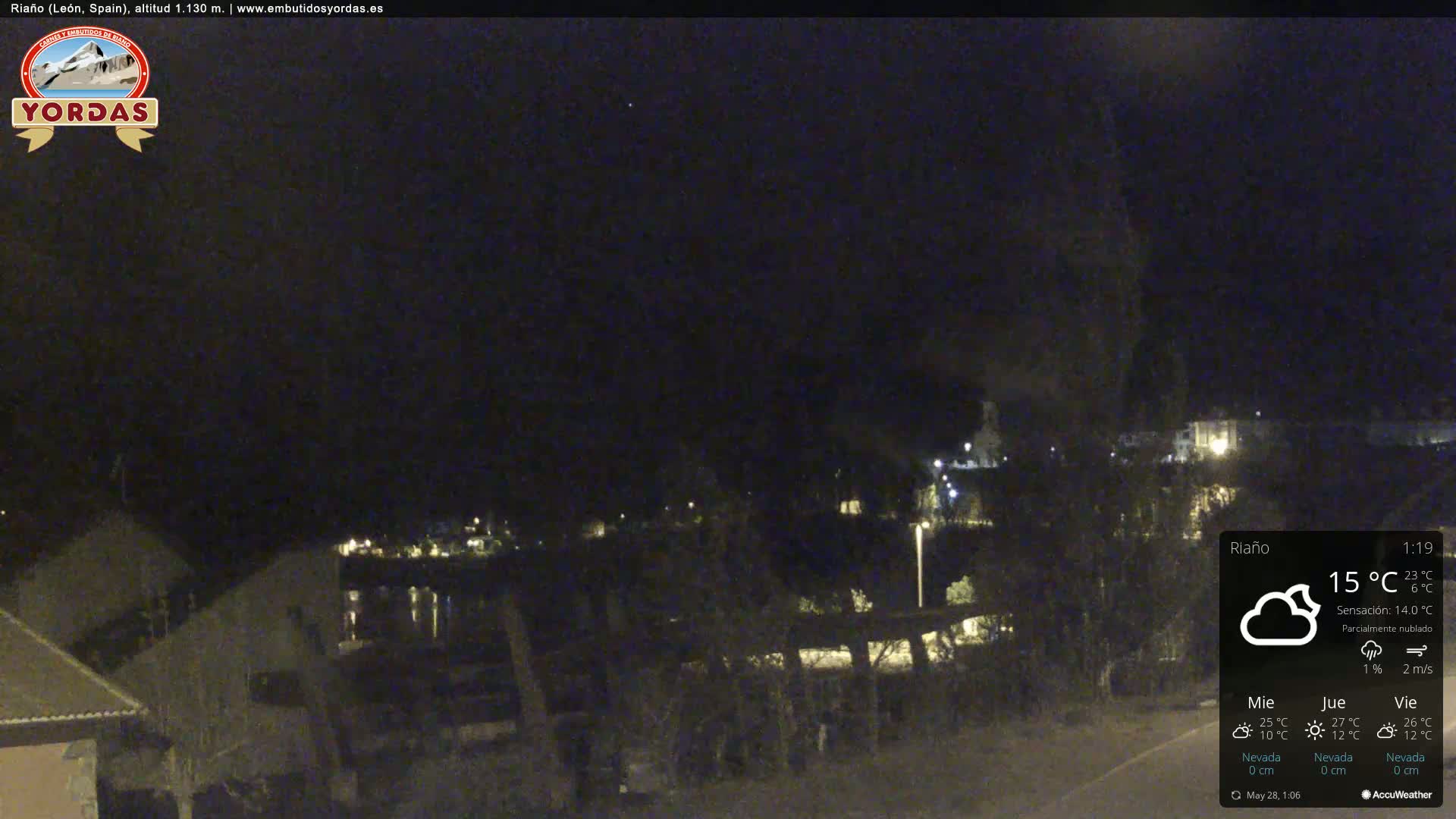 A nighttime view of a small town with some lights visible, under partly cloudy skies.