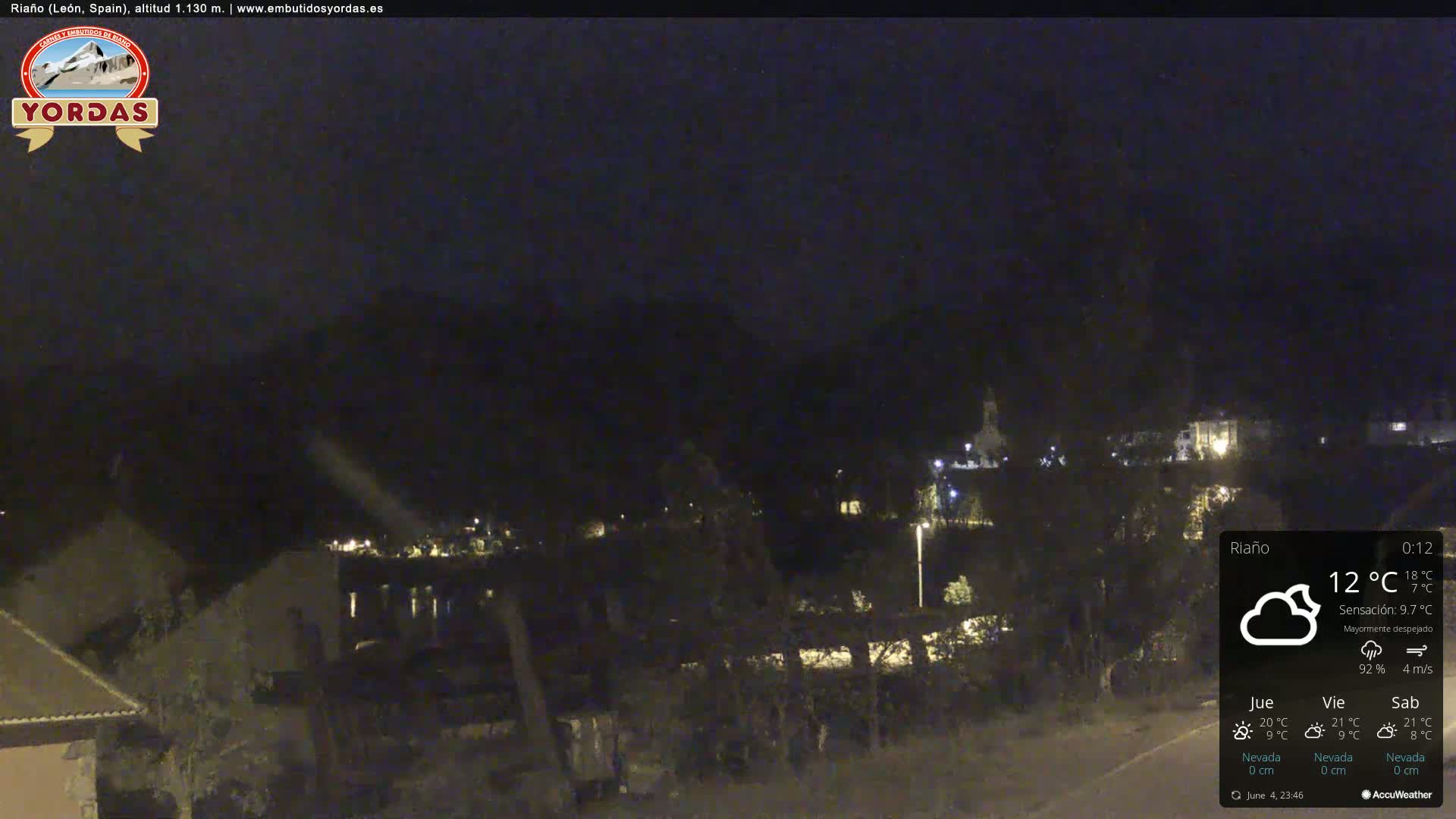 A nighttime view of a small town nestled in a valley, under a mostly clear sky.