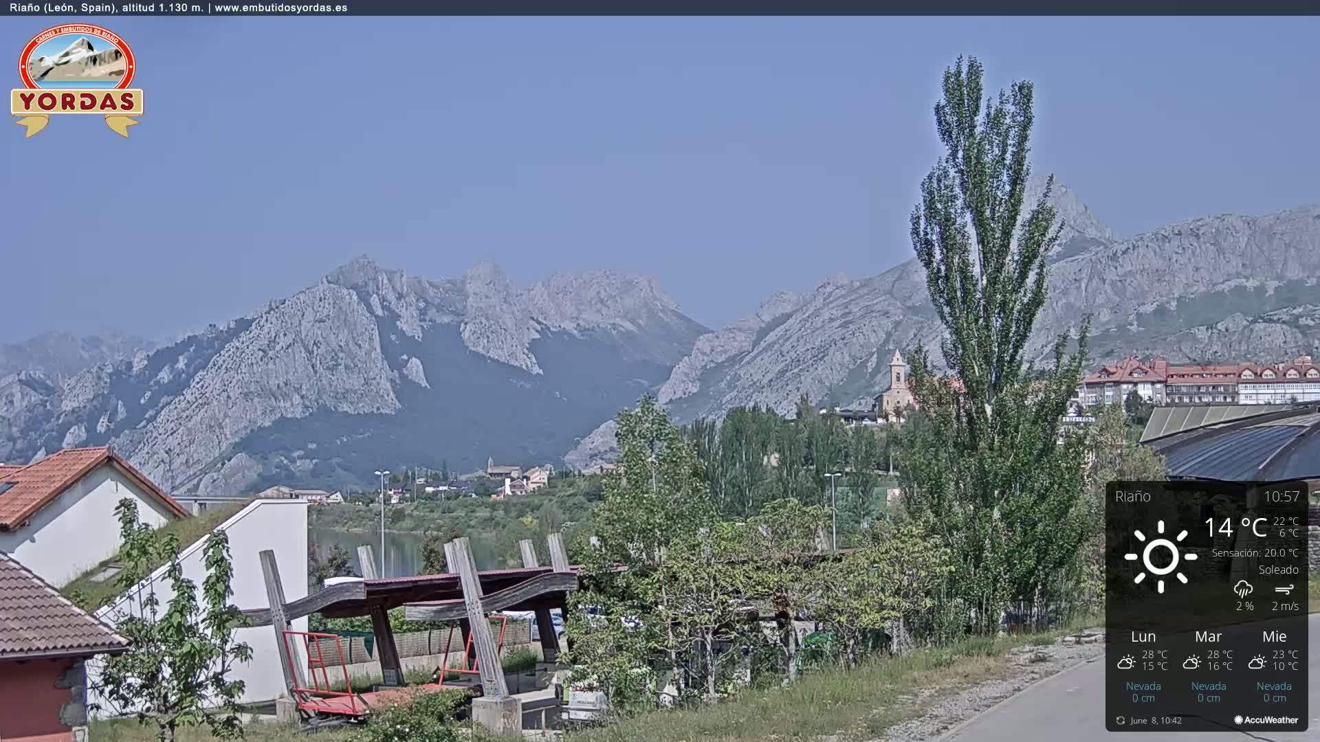 A sunny day reveals a town nestled at the foot of a mountain range, with a playground visible in the foreground.