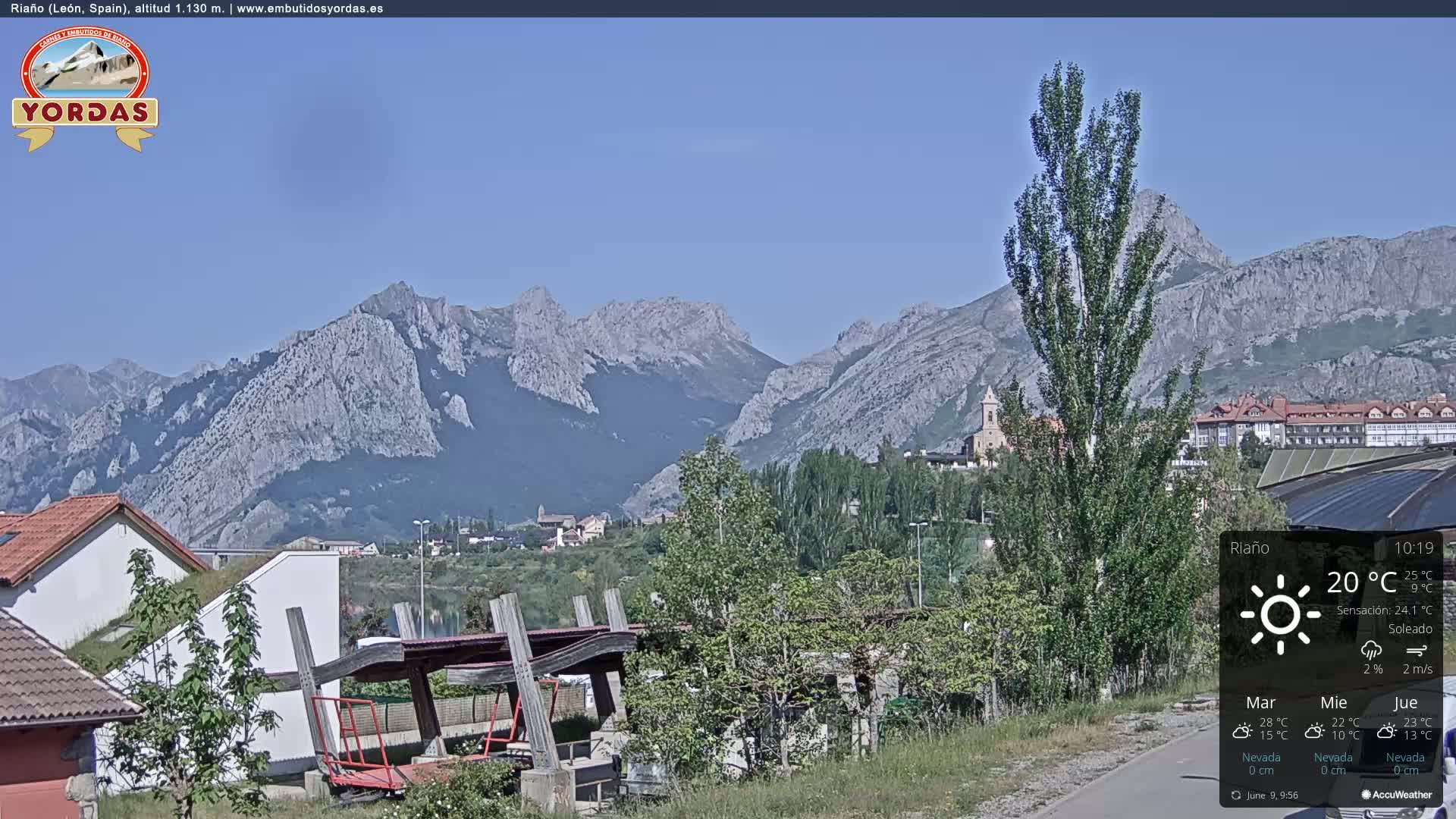 A sunny view of a town nestled in a valley, with mountains in the background.