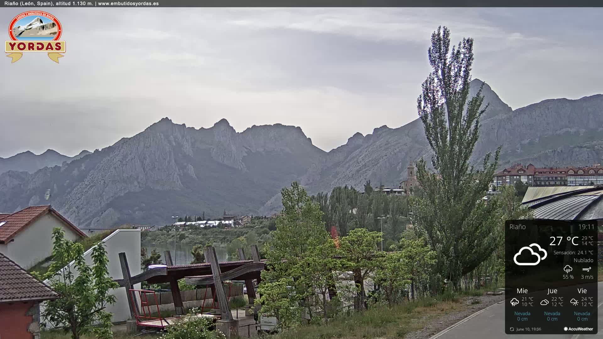 A cloudy day reveals a town nestled at the base of a large mountain range.