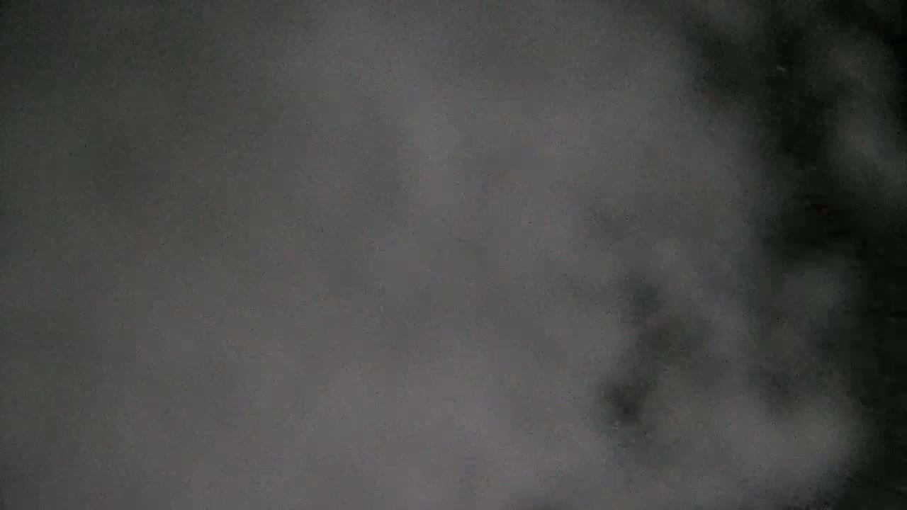 A blurry, dark gray image with indistinct shapes resembling shadows or fog.