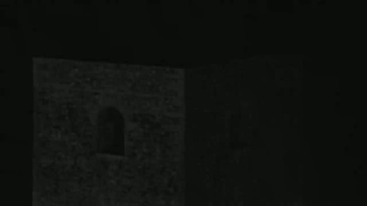A dark stone structure with a small arched window is visible at night.