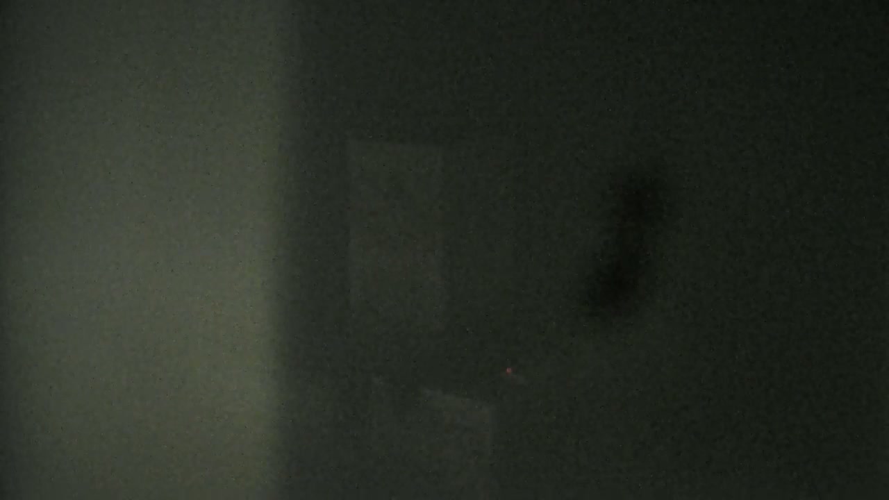 A blurry, dark image shows a shadowed, textured wall and a dimly lit, indistinct object.