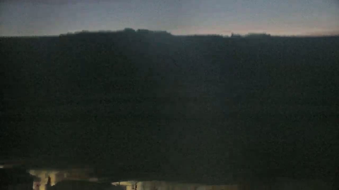 A dark landscape is shown at twilight, with a faint light illuminating the bottom edge.