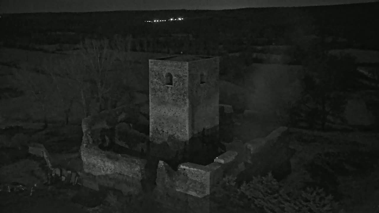A stone tower, part of a larger ruined structure, stands under a dark night sky.