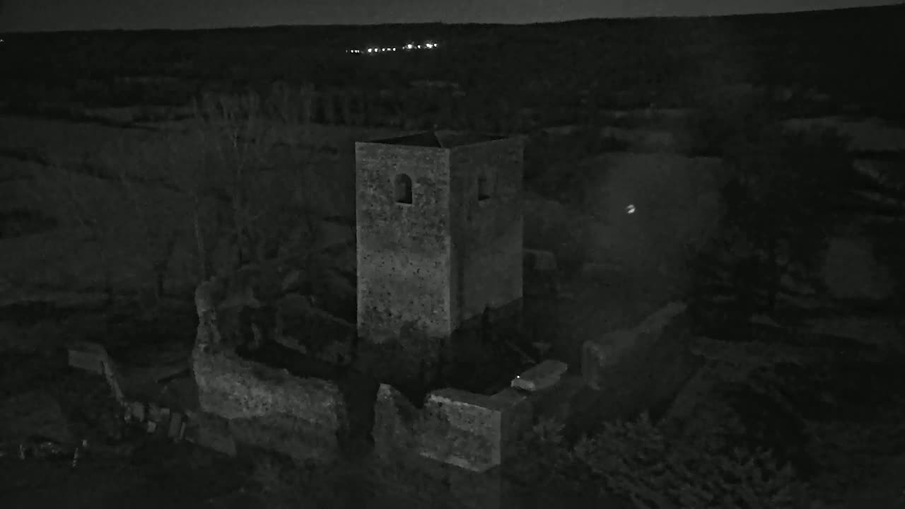 A stone tower, part of a larger ruined structure, stands under a dark night sky.