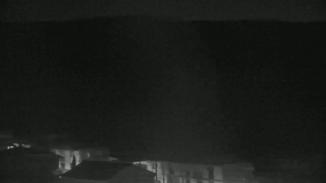 A nighttime, low-light view shows dimly lit buildings at the bottom of the frame against a dark sky.