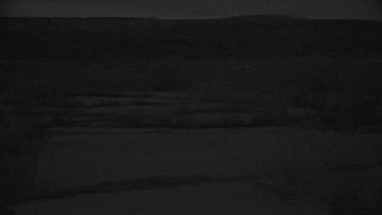 A dark, nighttime view of a flat, seemingly rural landscape under a cloudy sky.