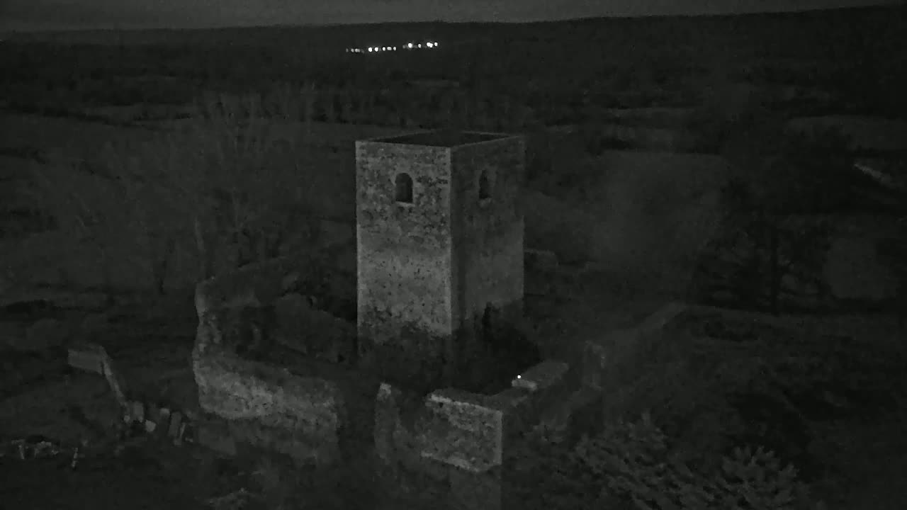 A stone tower, part of a larger stone ruin, stands under a dark night sky.