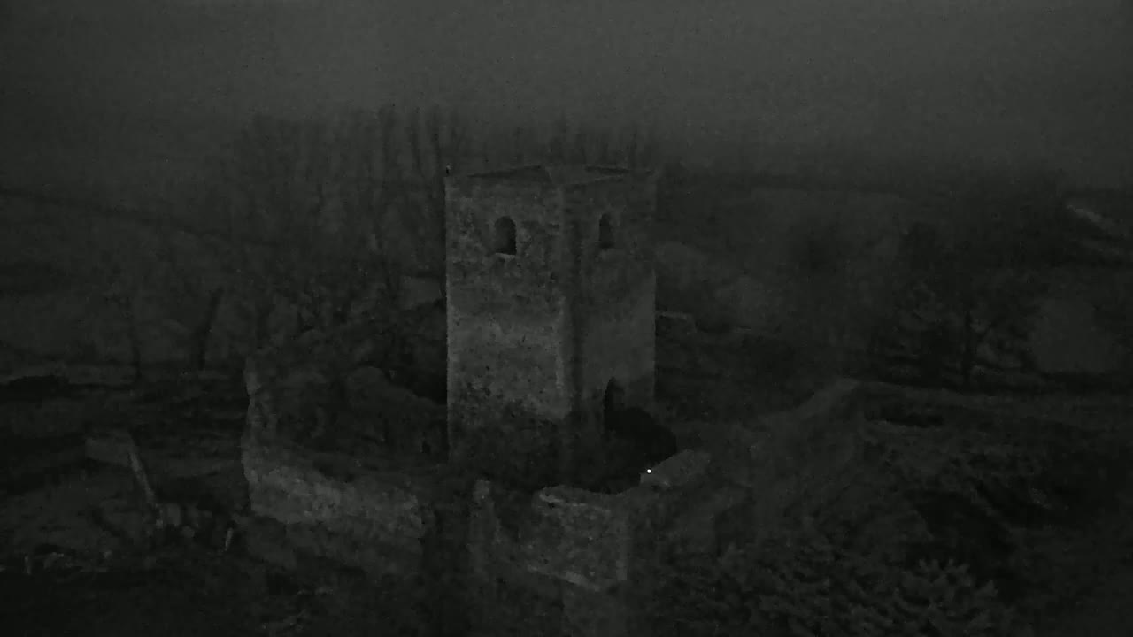A stone tower, possibly a ruin, stands amidst a foggy landscape of trees and low-lying structures.