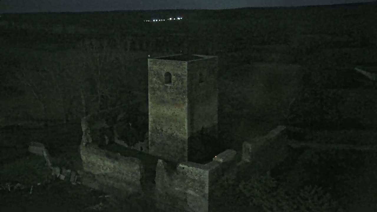 A stone tower, part of a larger ruined structure, stands under a dark night sky.