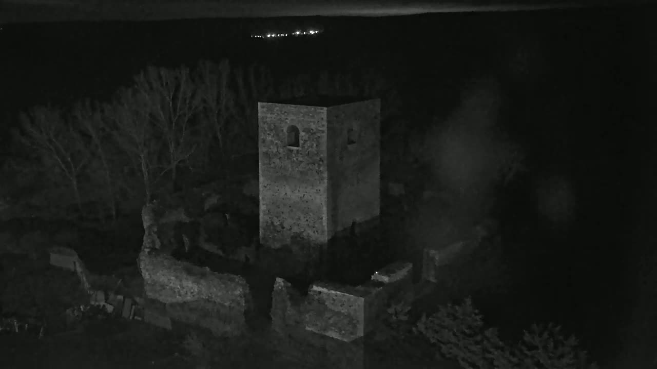 A stone tower, part of a larger ruined structure, is visible at night under a dark sky.