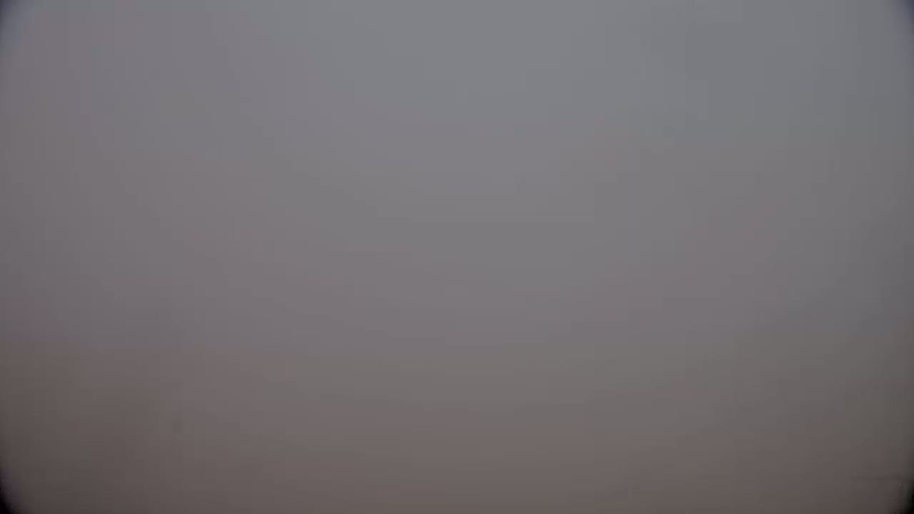 A blurry, gray image shows a foggy or hazy sky.