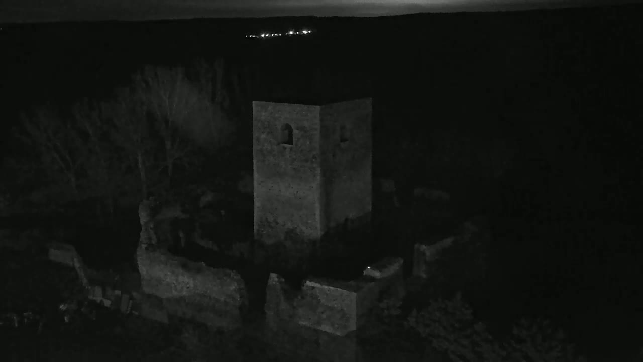 A stone tower and surrounding ruins are visible at night under a dark sky.